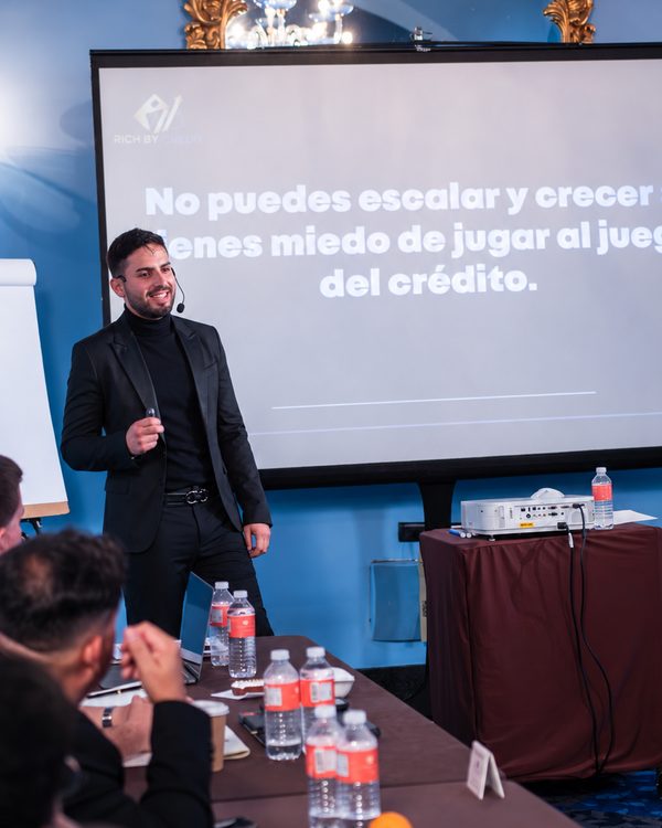 Oscar M. Heredia González, fundador de Rich By Credit, presentando frente a una pantalla con el logo de Rich By Credit